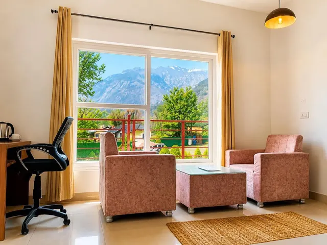 Room with sofa set, study desk and a window onto the garden and mountains